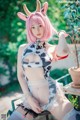 A woman with pink hair wearing a cow costume.