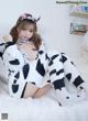 A woman in a cow costume sitting on a bed.