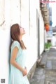 A woman leaning against a wall with her eyes closed.