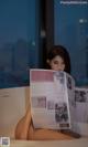 A woman sitting in a bathtub reading a newspaper.