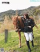 A woman standing next to a brown horse in a field.