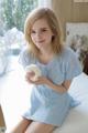 A young woman sitting on a bed holding a white ball.