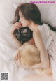 A woman laying on a bed holding a fluffy cat.