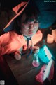 A little girl in a witches hat and glasses sitting at a table.