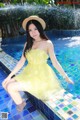 A woman in a yellow dress sitting on the edge of a pool.