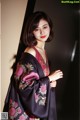 A woman in a black and pink kimono posing for a picture.