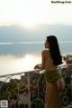 A naked woman standing on a balcony overlooking the ocean.