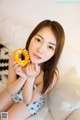 A woman sitting on a bed holding a donut in her hand.