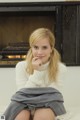 A woman sitting on a couch in front of a fireplace.