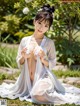 A woman in a white kimono sitting on the ground.