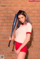 A woman holding a baseball bat in front of a brick wall.