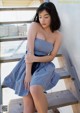 A woman in a blue and white dress sitting on a wooden staircase.