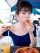 A woman sitting at a table eating a slice of pizza.