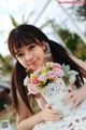 A woman holding a vase of flowers on a table.