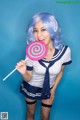 A woman in a sailor outfit holding a lollipop.