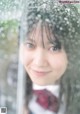 A woman in a school uniform holding an umbrella.