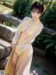 A woman in a yellow and white kimono posing for the camera.