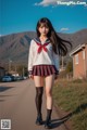 A woman in a school uniform is walking down the street.