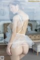 A woman in a white lingerie standing in front of a window.