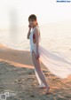 A woman in a white dress standing on a beach.